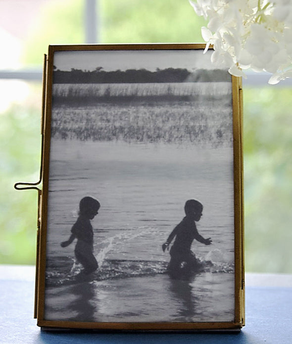 Brass Picture Frame with a simple to open and close clasp detail. It holds a 4" x 6" photo and has a photo of two kids playing in water.