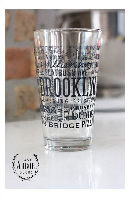 Pint Glass featuring Brooklyn, New York with highlights from the town in black screen print.